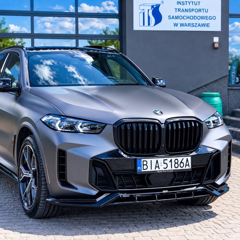 Matowy BMW X5 lub X6 M w kolorze grafitowym, zaparkowany przed budynkiem studia