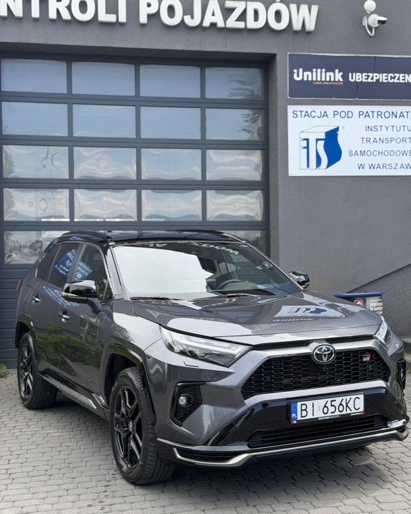 Szary Toyota RAV4 zaparkowany przed bramą studia
